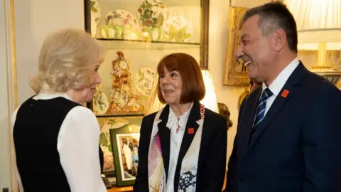 PA Media Camilla, Pelicot and Agopian speaking in Clarence House, with a display of ornate crockery behind them.
