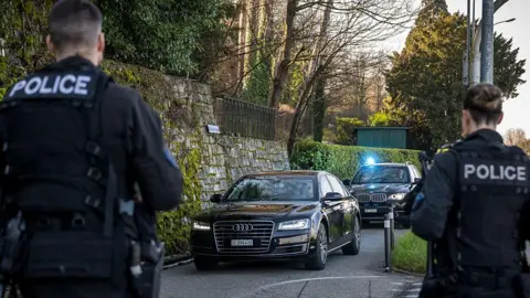AFP Swiss police officers stand by as a convoy arrives at the Omani ambassador residence for new round of indirect talks between the United States and Iran, in Geneva, Switzerland (26 February 2026)