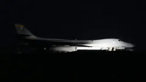 PA Media A white bomber plane is pictured flying through the dark night's sky.